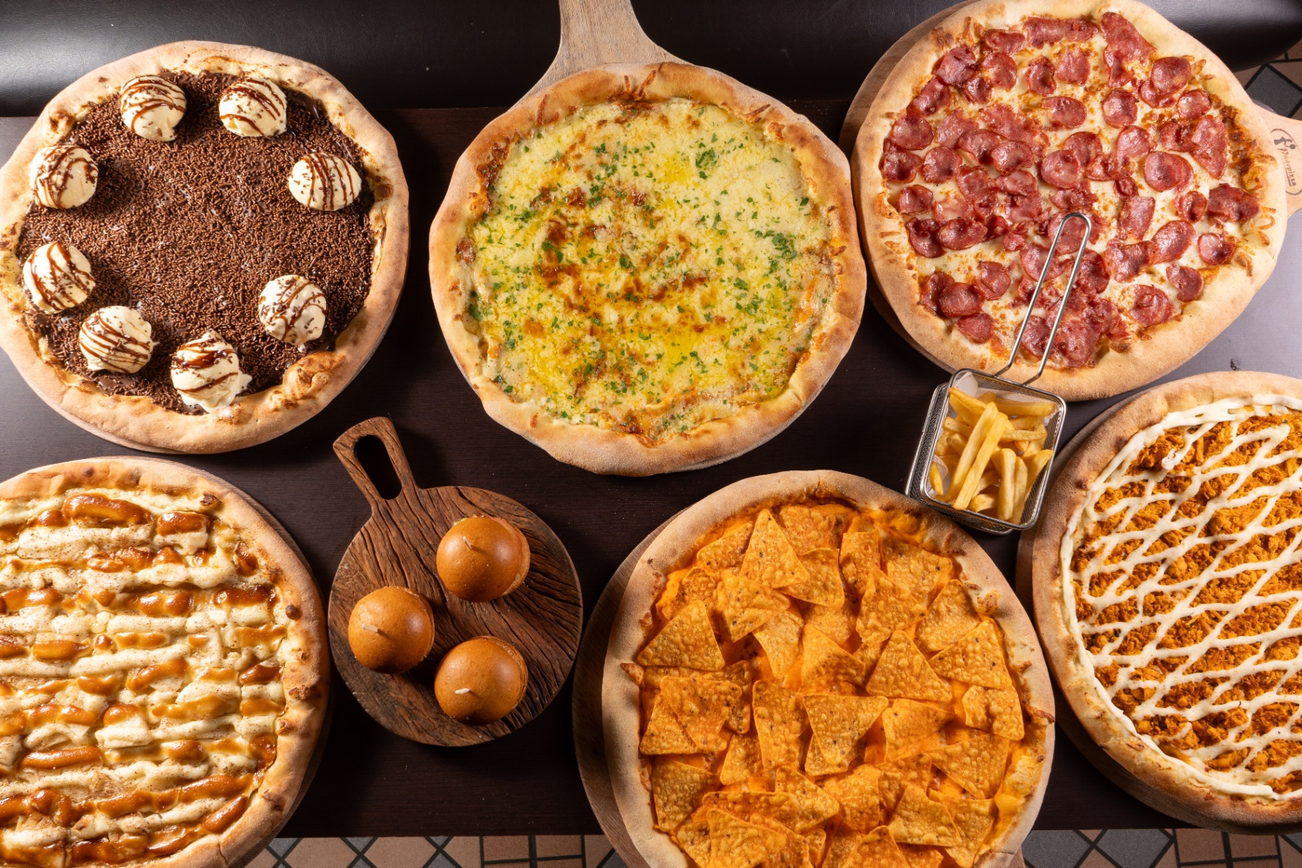 Mesa cheia do rodízio Fogaça's com pizzas, mini hambúrguer e batata